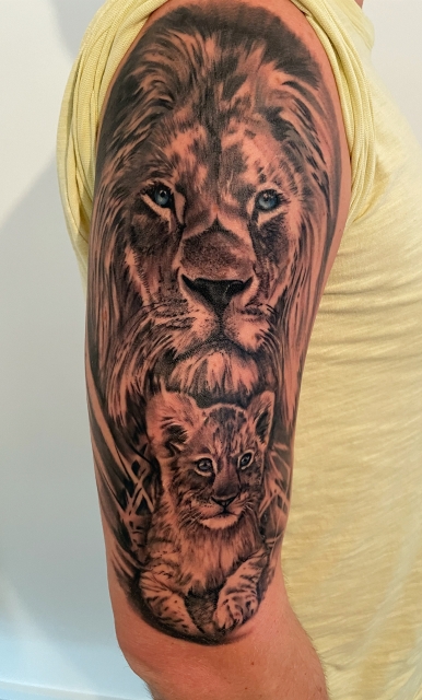 Löwe mit Löwenbaby auf Oberarm